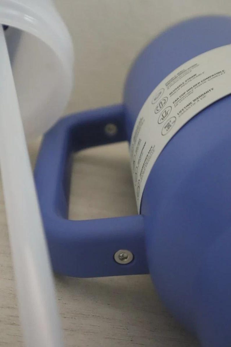 Puede incluir: Primer plano de un vaso azul con asa y pajita blanca. El vaso tiene un asa y una etiqueta blanca con texto. La pajita es blanca y est&aacute; colocada cerca del vaso. El vaso es de un material liso.