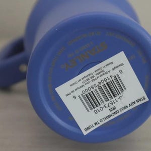 Puede incluir: Un vaso Stanley azul de 40 oz con asa. La parte inferior del vaso tiene una etiqueta blanca con informaci&oacute;n del producto y un c&oacute;digo de barras. Fabricado en China.