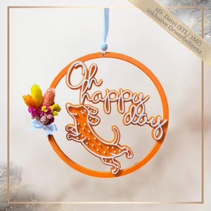 Könnte beinhalten: Orangener, kreisförmiger Wandschmuck mit dem Schriftzug "Oh happy day" und einer Dackel-Illustration mit weißen Punkten. Ein kleiner Strauß bunter Trockenblumen ist mit einem blauen Band befestigt.