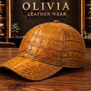 May include: A baseball cap crafted from golden-brown leather with a prominent embossed crocodile skin texture. The cap features a structured six-panel crown, a curved brim, and a small button at the top center, showcasing a detailed scale pattern.