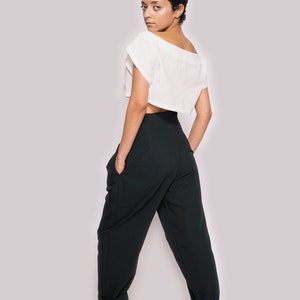 K&ouml;nnte beinhalten: Eine Person tr&auml;gt ein wei&szlig;es, bauchfreies Oberteil und eine schwarze Hose mit umgeschlagenen Beinen. Sie tr&auml;gt schwarze Sandalen.
