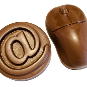 May include: Two brown chocolate sweets: one shaped like a computer mouse and the other a round disc with an at symbol. The mouse has a scroll wheel and two buttons. The sweets are on a white background.