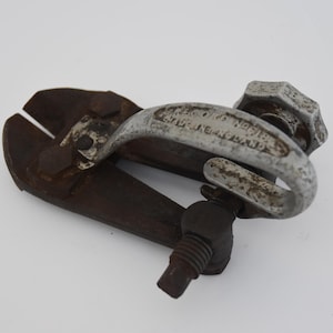 May include: A vintage metal bolt cutter tool featuring a dark, oxidized iron cutting head and a curved, light grey handle with visible wear. The handle is embossed with the text 'MADE IN ENGLAND' and includes a large, hexagonal adjustment knob.