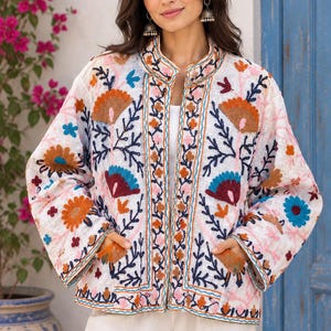 May include: A white long-sleeve jacket featuring an intricate floral embroidery pattern in shades of orange, blue, and pink. The jacket has a mandarin collar, an open front design, and two front pockets, with decorative stitching along the edges.