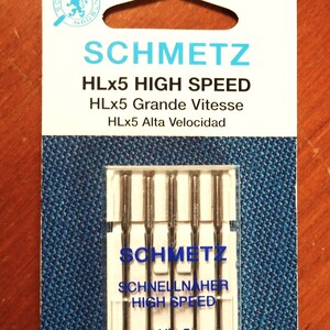 Op de afbeelding: Een verpakking SCHMETZ HLx5 High Speed naaimachinenaalden. De verpakking is wit met blauwe accenten en toont de merknaam en naaldspecificaties. De naalden zijn maat 90/14.