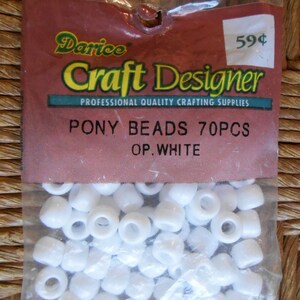 May include: A clear plastic bag filled with white pony beads. The bag has a red and brown label with the text "Darice Craft Designer" and "Pony Beads 70pcs OP. White."