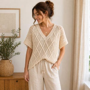 May include: Cream-colored, short-sleeved top with a V-neck and diamond-patterned crochet design. The top is paired with light beige pants with a drawstring. The outfit is casual and comfortable, suitable for everyday wear.