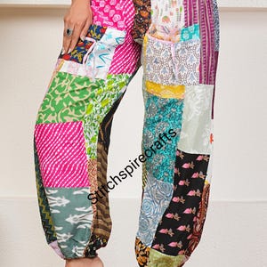 May include: Patchwork trousers featuring a variety of colorful fabric squares with diverse patterns including floral, geometric, and striped designs. The pants have an elasticized waistband and gathered cuffs at the ankles. The text Stitchspirecrafts is visible.
