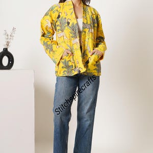 May include: A bright yellow quilted jacket featuring a vibrant jungle print with tigers, toucans, and palm trees. The jacket has long sleeves, an open front, and two front patch pockets. The text Stitchspirecrafts is visible on the jacket.