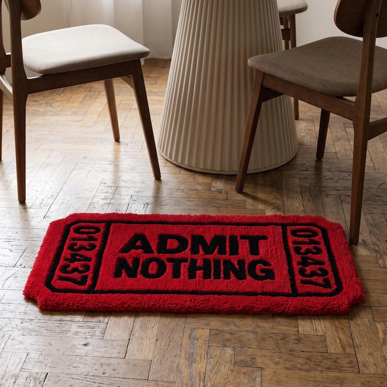 Puede incluir: Una alfombra rectangular roja con forma de boleto vintage con bordes negros y texto negro que dice ADMIT NOTHING. La alfombra presenta el n&uacute;mero 013437 impreso en negro tanto en el lado izquierdo como en el derecho del dise&ntilde;o del boleto.