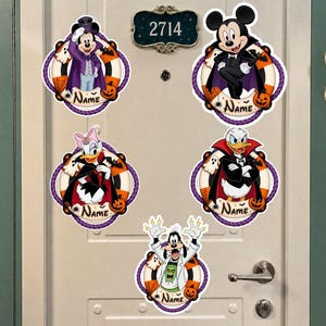 May include: Five circular Halloween-themed door signs featuring Disney characters: Mickey Mouse as a vampire, Mickey Mouse in a cape, Daisy Duck, Donald Duck, and Goofy as a scientist. Each sign has a rope border, pumpkins, and a space for a name.