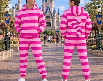 May include: A matching set consisting of a hooded sweatshirt and sweatpants featuring horizontal hot pink and light pink stripes. The back of the hoodie displays a large, curved, striped tail graphic. The set is paired with white trainers.