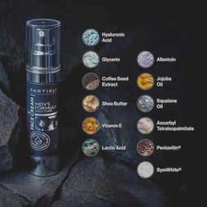 Op de afbeelding: Een donkerblauwe Particle gezichtscr&egrave;mefles met een doorzichtige pomptop. Het etiket luidt "MEN'S FORMULA DAILY CARE" en vermeldt ingredi&euml;nten zoals hyaluronzuur, vitamine E en sheaboter. De achtergrond is donker met ingredi&euml;ntenillustraties.
