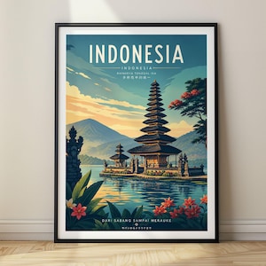 Op de afbeelding: Een ingelijste reisposter met een tempel met meerdere verdiepingen aan een meer in Indonesië. De tekst luidt INDONESIA, BHINNEKA TUNGGAL IKA en DARI SABANG SAMPAI MERAUKE. De scène toont bergen, een blauwe lucht en rode bloemen op de voorgrond.