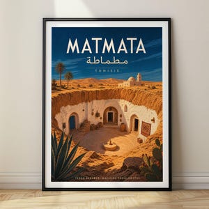May include: A framed travel poster featuring a stylised illustration of the troglodyte dwellings in Matmata, Tunisia. The artwork depicts a sunken courtyard with white arched entrances, desert landscape, palm trees, and blue sky with text.