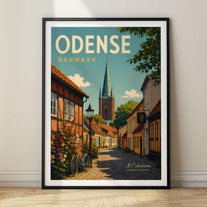 Könnte beinhalten: Ein gerahmtes Reiseplakat von Odense, Dänemark, mit einer gepflasterten Straße, Fachwerkhäusern, einem Fahrrad, einem hohen Kirchturm und blühenden Blumen. Der Text lautet ODENSE, DANMARK und H.C. Andersen Byens Eventyr.