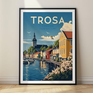 Puede incluir: Un póster de viaje enmarcado de Trosa, Sverige, que muestra un canal azul con barcos, la torre de una iglesia y casas coloridas, incluido un edificio amarillo con una bandera sueca. El cielo es azul con nubes blancas y el texto dice Trosa Sverige.