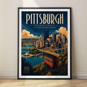 May include: A framed travel poster of the Pittsburgh, Pennsylvania skyline featuring the city name, the text 'LA CIUDAD DE LOS PUENTES', and 'STEEL CITY EST. 1758'. The illustration shows skyscrapers, yellow bridges, a river, and a red funicular car.