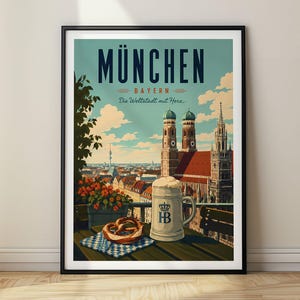 Peut inclure: Une affiche de voyage encadrée représentant Munich, en Allemagne, avec le texte MÜNCHEN BAYERN Die Weltstadt mit Herz. L'illustration montre une chope de bière, un bretzel et la cathédrale Frauenkirche sous un ciel bleu nuageux.