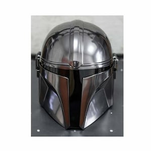 May include: A metallic silver Mandalorian helmet with a black visor. The helmet has a smooth, reflective surface with vertical ridges on the top. The design features angular shapes and a distinctive T-shaped visor.