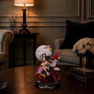 Könnte beinhalten: Eine detaillierte Anime-Figur einer weiblichen Figur mit langem dunklem Haar, die ein rosa-weißes Outfit trägt und dynamisch vor einem großen weißen Mond posiert. Der Sockel zeigt rote, wirbelnde Elemente, rosa Kirschblüten und gelbe Akzente.