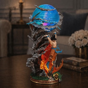 May include: A detailed figurine of a character with spiky black hair, wearing orange and blue attire, amidst a fiery, smoky display. A blue orb with light effects sits above the figure. The base is gold and green.