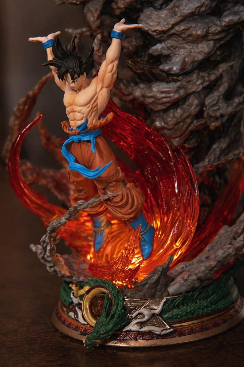 May include: A detailed figurine of a muscular character in a dynamic pose, surrounded by fiery orange and red energy effects. The figure wears orange pants, blue boots and wristbands, and a blue sash. The base features a dragon design.