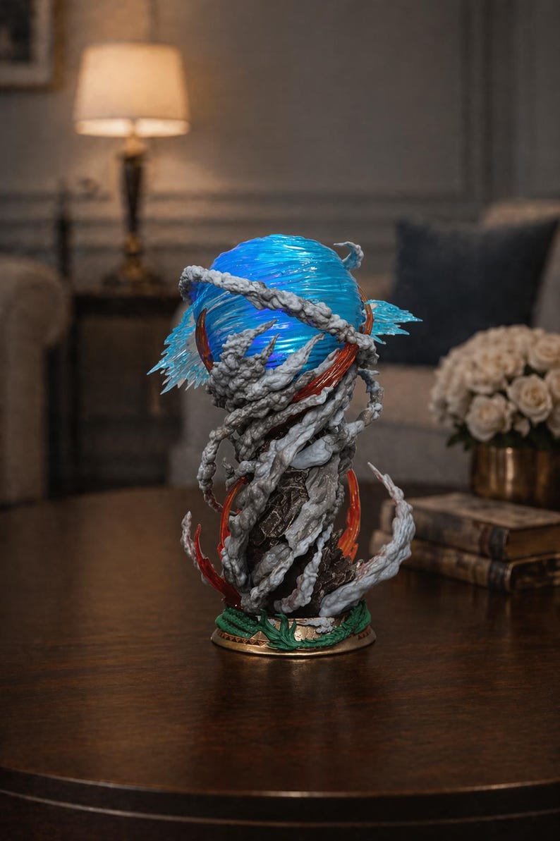 May include: A detailed sculpture featuring a blue orb with swirling patterns, surrounded by gray, cloud-like formations and red accents. The base has a green and gold trim. The artwork is displayed on a dark wooden table.