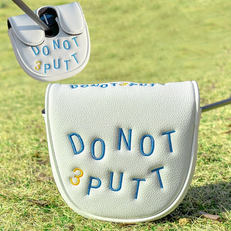 Pu&ograve; includere: Copertura bianca per la testa del putter da golf con testo ricamato blu che recita "DO NOT PUTT" e un "3" dorato. La copertura &egrave; su una superficie erbosa verde. La mazza da golf &egrave; inserita nella copertura.