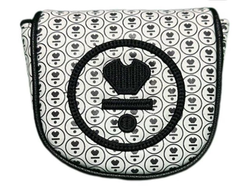May include: A white golf putter cover with a repeating pattern of black circles containing a heart and a line. The cover has a black border and a large black emblem with a crown and other shapes.