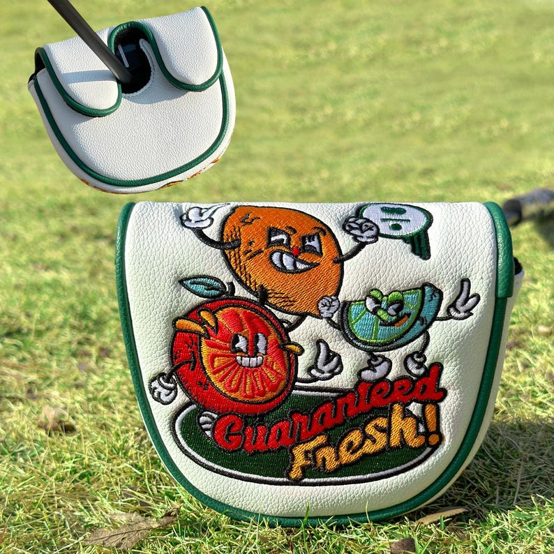 Pu&ograve; includere: Copertura per putter da golf bianca con finiture verdi e un design di frutta a cartoni animati. La copertura presenta un'arancia, un kiwi e un'anguria con la scritta "Guaranteed Fresh!" in rosso e verde.