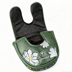 May include: Green golf putter cover with white floral embroidery and black plush interior. The cover features the text "L.A.B. GOLF" and a logo. The exterior is a textured, leather-like material.