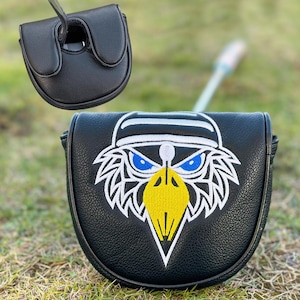 Pu&ograve; includere: Copertura per putter da golf nera con un design di aquila ricamata. L'aquila ha occhi blu, un becco giallo e una copertura per la testa bianca e nera. La copertura &egrave; realizzata in un materiale strutturato e viene mostrata sull'erba.