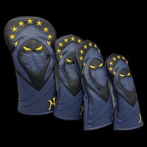 May include: A set of four golf club head covers. Each cover is navy blue with a black and yellow design of a hooded figure with yellow eyes. The top of each cover has a ring of yellow stars. The letter "N" is on the side.