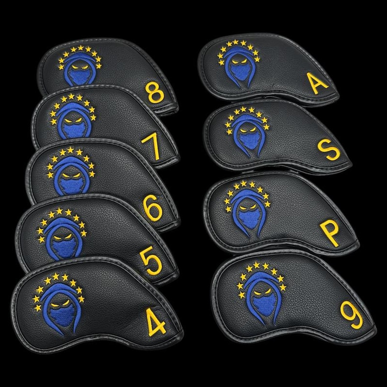 May include: A set of black golf club head covers. Each cover has a blue ninja design with yellow star accents and a yellow number or letter. The covers are displayed against a black backdrop.