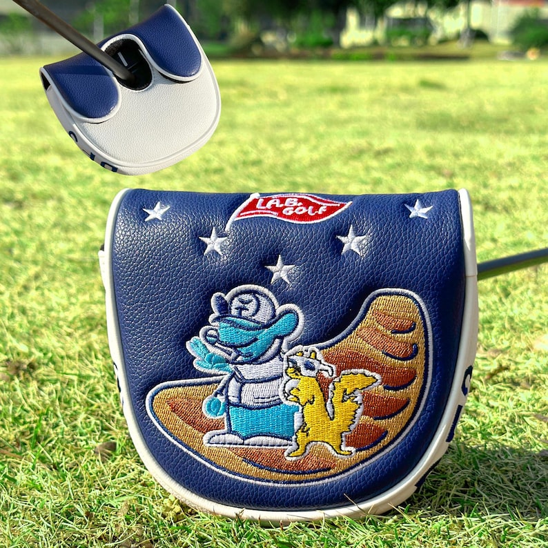 Pu&ograve; includere: Una copertura per la testa del putter da golf blu navy e bianca con un design a cartoni animati. La copertura presenta un'anatra e uno scoiattolo su una superficie marrone, con stelle e la scritta "LAB Golf". La copertura &egrave; in pelle.