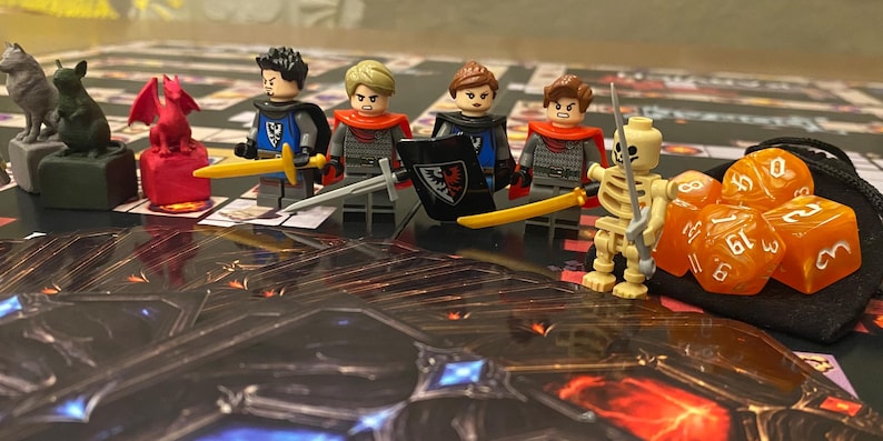 Puede incluir: Una configuraci&oacute;n de juego de mesa con minifiguras de Lego de caballeros y un guerrero esqueleto, dados y piezas de juego. Los caballeros est&aacute;n armados con espadas y escudos, y los dados son naranjas. El tablero del juego tiene un tema de fantas&iacute;a.