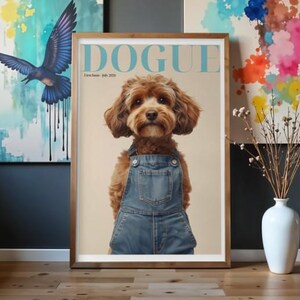 May include: A framed poster featuring a brown dog wearing blue denim overalls. The text at the top reads DOGUE, with First Issue July 2024 printed below. The dog has floppy ears and a light brown muzzle, centred against a beige background.