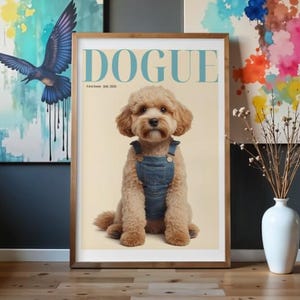 Pode incluir: Um cartaz emoldurado intitulado DOGUE com o texto First Issue- July 2026, apresentando um cão de pelo encaracolado castanho claro a usar jardineiras de ganga azul. O cão está centrado num fundo creme, numa moldura de madeira na parede.