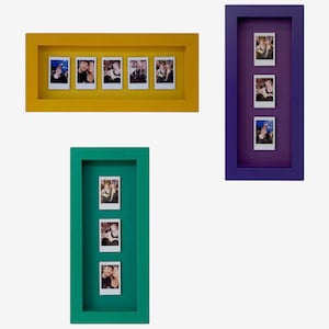 May include: Three rectangular shadow box frames in yellow, purple, and teal. The yellow frame holds five small square photographs in a horizontal row. The purple and teal frames each hold three small square photographs in a vertical column.