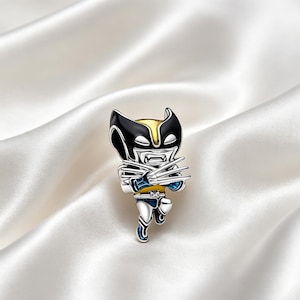 May include: A metallic enamel pin featuring a stylized character with a black and yellow mask, blue and yellow suit, and silver claws extended from each hand. The character is depicted in a dynamic pose with a fierce expression and sharp details.