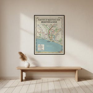 Może przedstawiać: Oprawiony wydruk ścienny zatytułowany Pubstops of Brighton & Hove, przedstawiający stylizowaną mapę lokalnych pubów w formie schematu komunikacji miejskiej. Projekt zawiera kolorowe linie, nazwy lokalizacji, legendę oraz niebieski obszar wybrzeża.