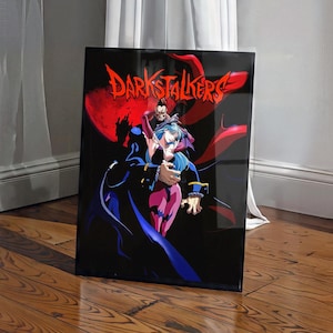 May include: A rectangular wall art print featuring the Darkstalkers logo in red text at the top. The artwork depicts a male character with dark hair and a female character with blue hair in a dark setting with a large red moon in the background.