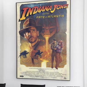May include: A rectangular poster for the video game Indiana Jones and the Fate of Atlantis. It features a large illustration of Indiana Jones wearing a fedora, silhouettes of camels, and two figures standing before a glowing golden structure.