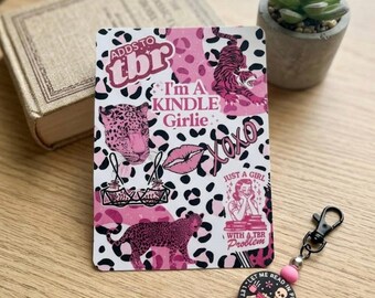 Könnte beinhalten: Eine rechteckige Karte mit einem rosa-weißen Leopardenmuster-Hintergrund und dem Text ADDS TO tbr, I'm A KINDLE GIRLIE, XOXO und JUST A GIRL WITH A TBR Problem, sowie Illustrationen von einem Tiger, Leoparden, Lippen und einer lesenden Person.