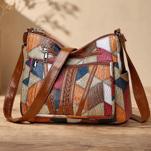 May include: A multi-colored patchwork crossbody bag with a brown leather strap. The bag features a geometric pattern of various colors, including red, blue, orange, and white. It has multiple zippered compartments and a braided detail on the front.