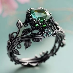 Peut inclure: Une bague en métal noir ornée d'une grande pierre précieuse verte à facettes rectangulaires, montée sur un support en forme de couronne. L'anneau présente des motifs complexes de vignes et de feuilles en relief, agrémentés de trois petites pierres claires.