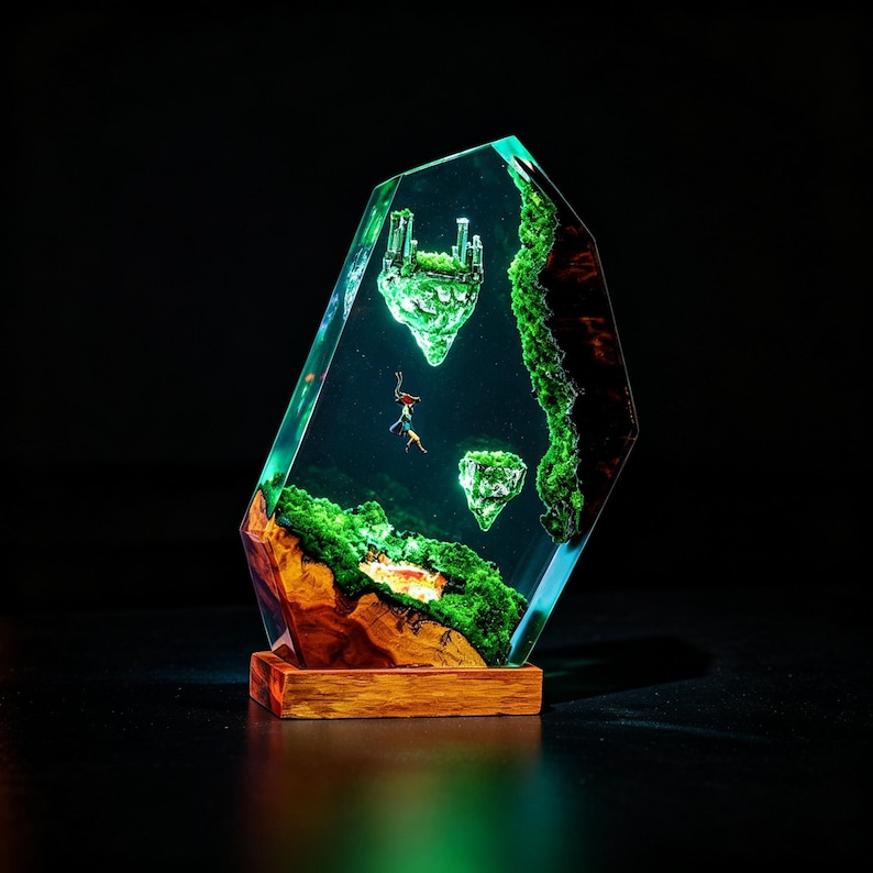 May include: A unique resin sculpture featuring a fantasy landscape with floating islands, lush green vegetation, and a miniature figure. The artwork is set on a wooden base, with a clear, faceted resin exterior. The sculpture has a dark background.