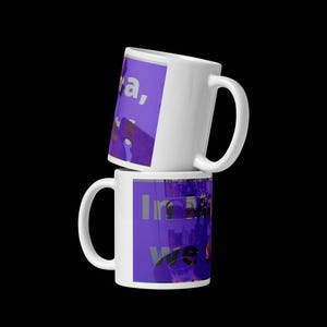 Peut inclure: Deux mugs en céramique blanche empilés. Chaque mug présente un graphisme violet avec du texte. Le mug du haut affiche "a,". Le mug du bas montre "In we". Les mugs sont sur fond noir.