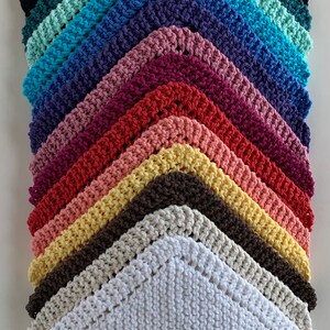 Puede incluir: Una pila de 12 pa&ntilde;os de cocina de ganchillo en varios colores, incluyendo blanco, beige, amarillo, naranja, rojo, rosa, morado, azul, turquesa y gris. Los pa&ntilde;os de cocina est&aacute;n dispuestos en forma triangular, con el pa&ntilde;o de cocina blanco en la parte inferior.